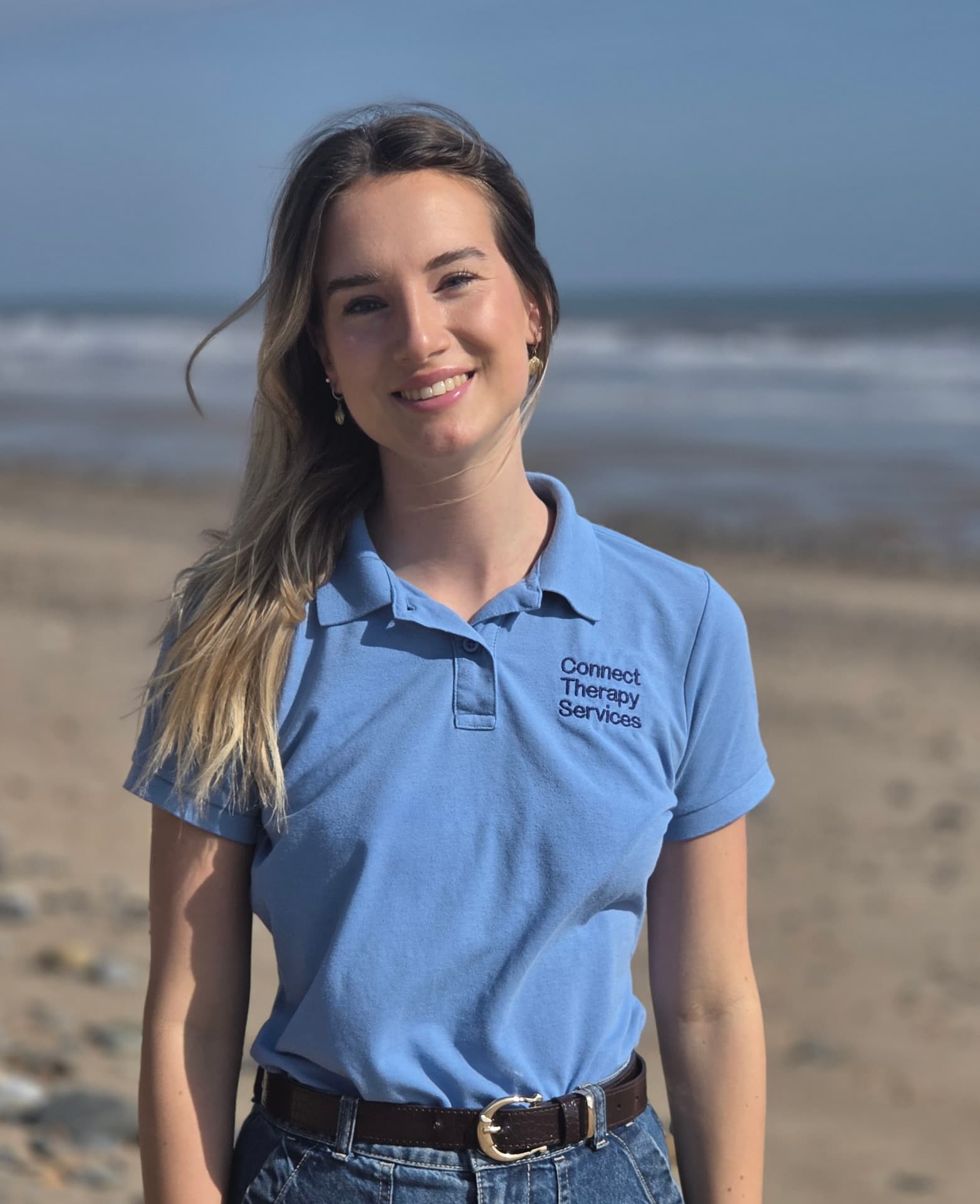 Abbie Turner smiling on the beach in a light blue Connect polo shirt