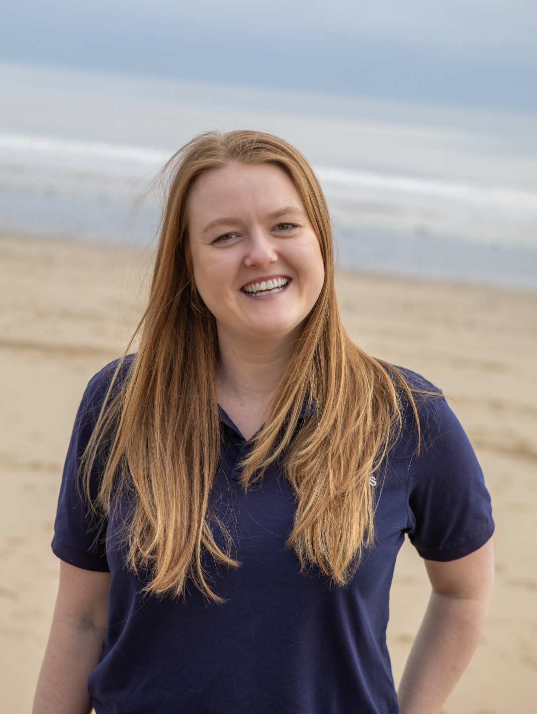 Alice Lee smiling on the beach in a navy polo shirt