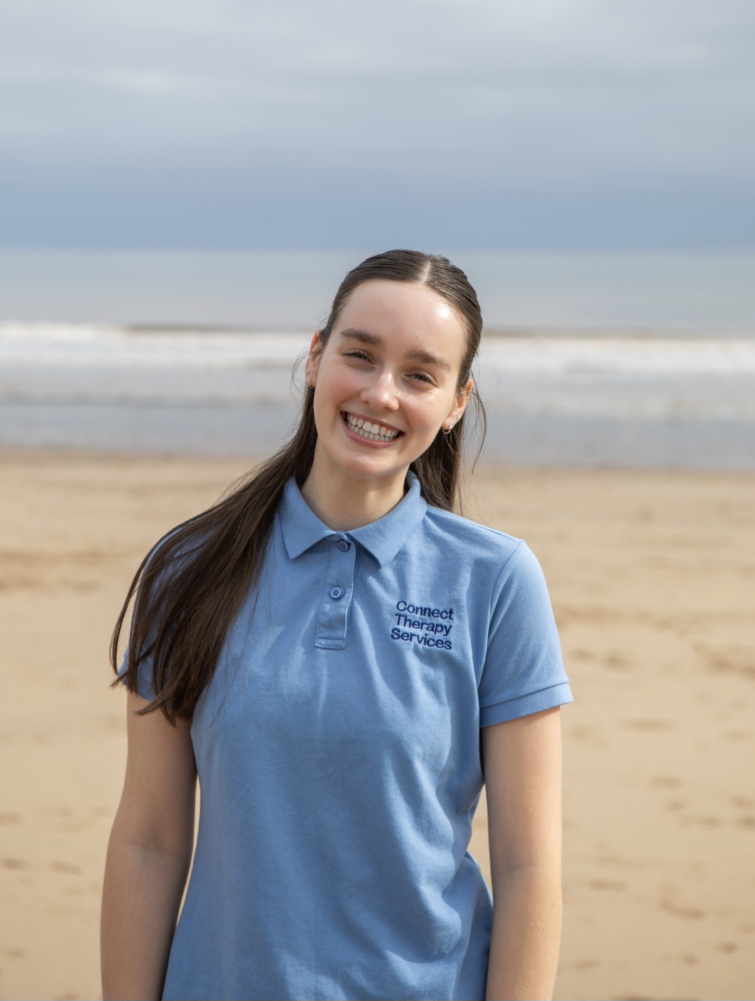 Lexie Ogram smiling on the beach in a light blue Connect polo shirt