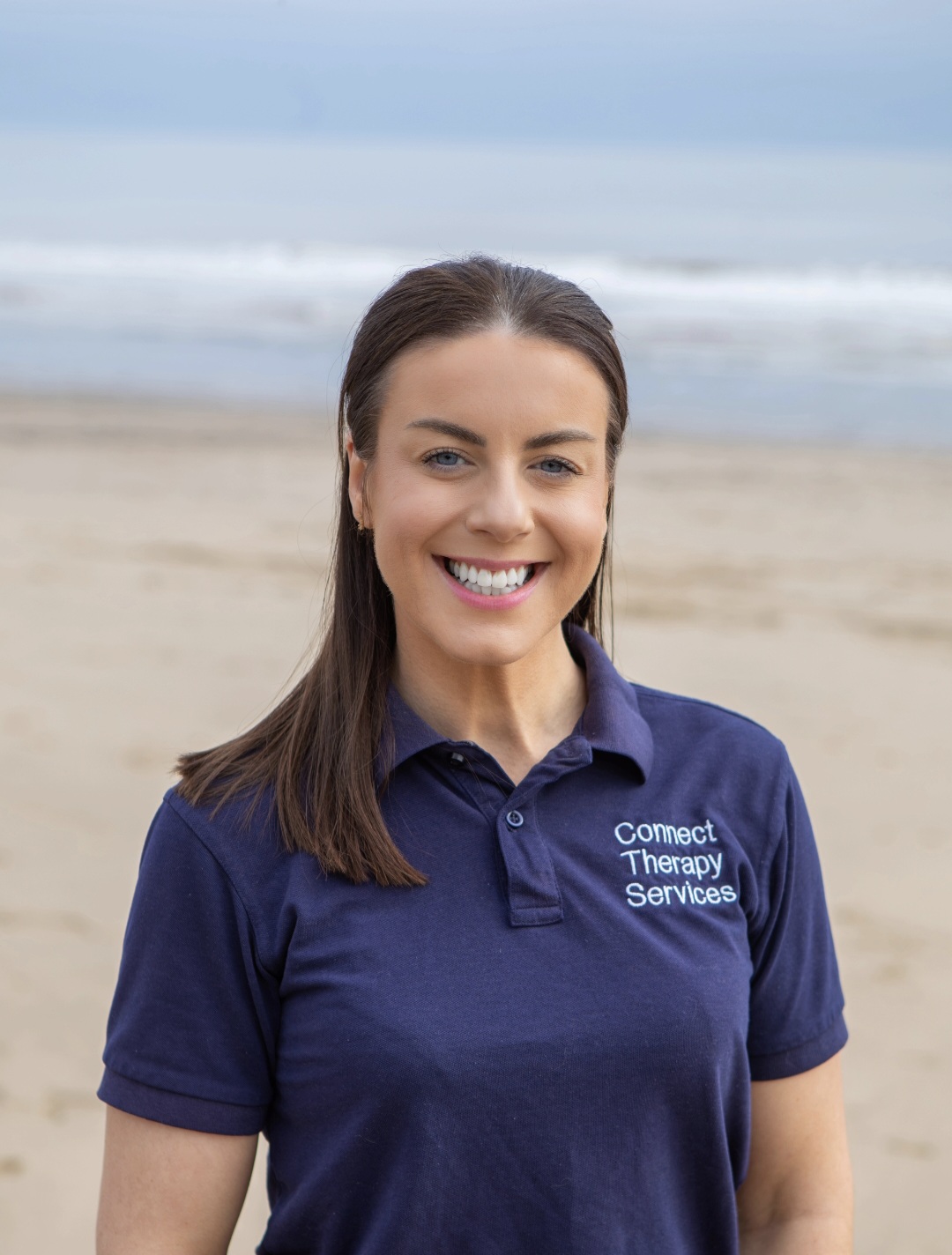 Scarlett Leedham smiling on the beach in a navy Connect polo shirt
