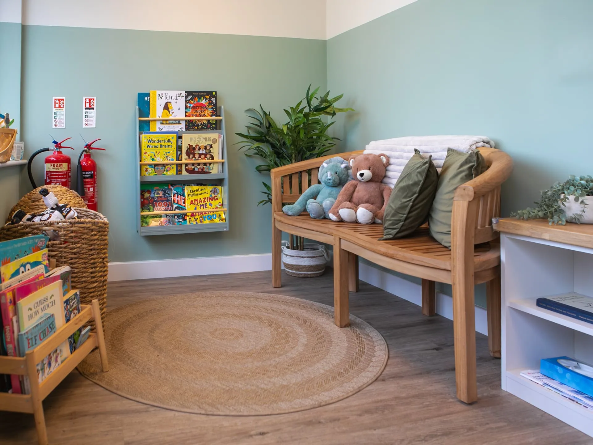 The Connect waiting area with a wooden bench, soft toys, cushions and a bookshelf of children's books