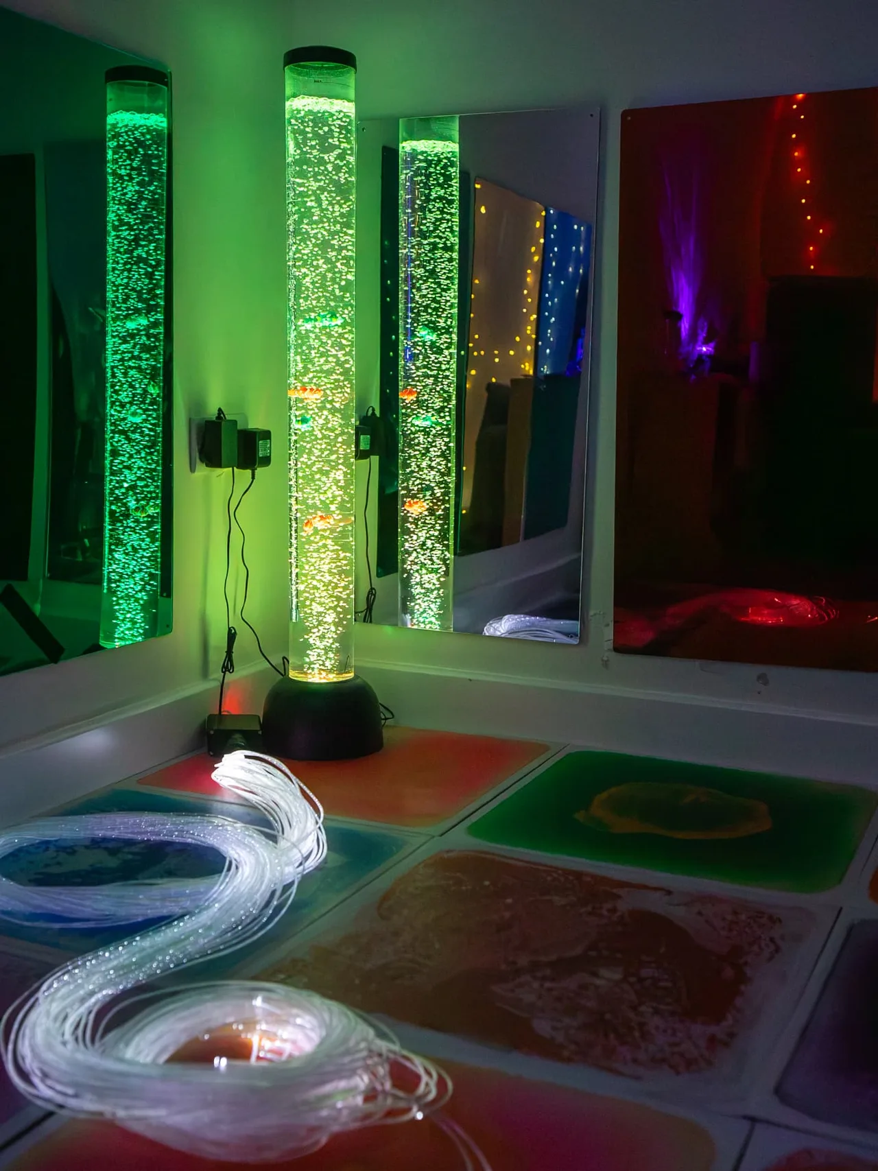 The bubble tube glowing green beside fibre-optic lights