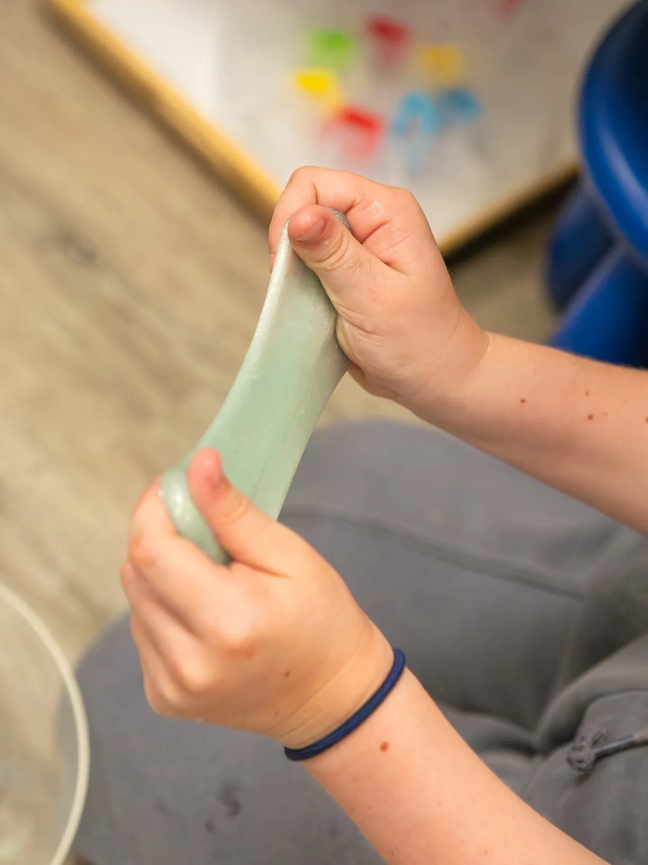 A child stretching green slime between their hands