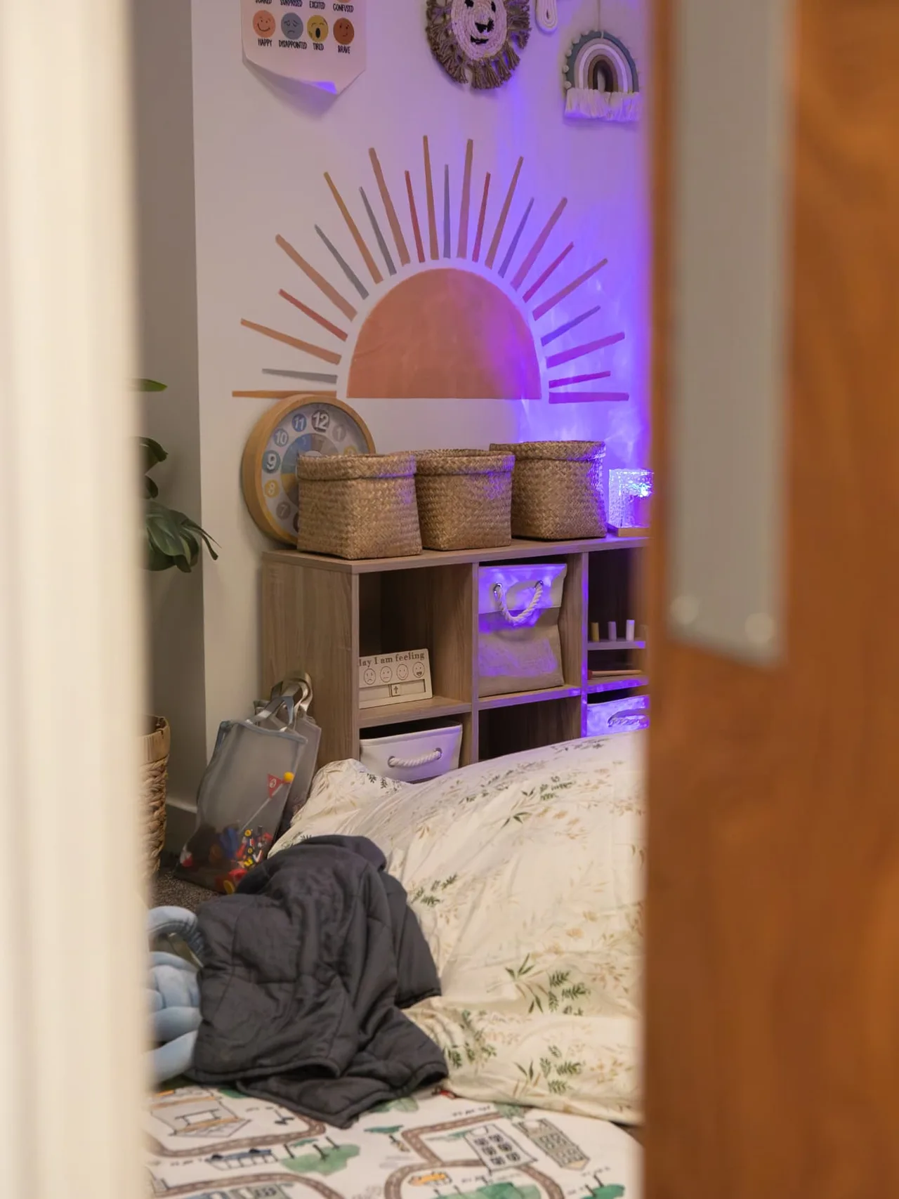 A cosy corner of the sensory room with a sun mural, beanbag and weighted blanket