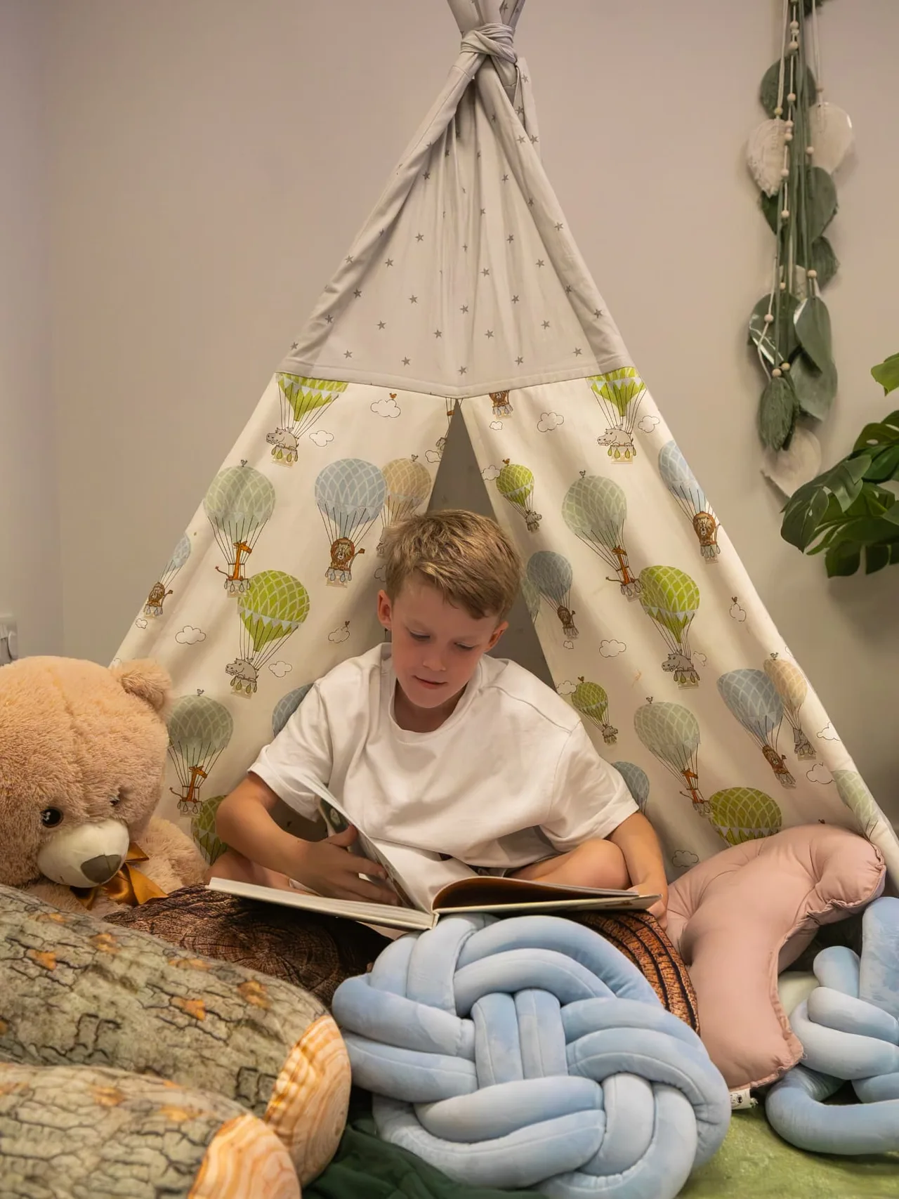 A boy reading inside the teepee in the sensory room
