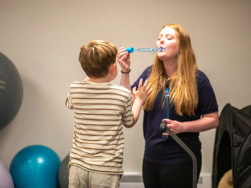 A Connect therapist blowing bubbles with a young boy during a therapy session