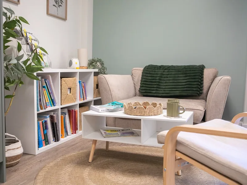 The Connect therapy room with a sofa, coffee table, bookshelves and soft green walls