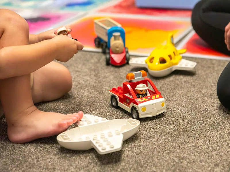 A child playing with toy vehicles on the carpet at the Connect clinic